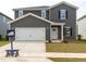 Two-story home featuring a white garage door, grey siding, black shutters, and a well-maintained lawn at 2250 Cherry Creek Rd, Haw River, NC 27258