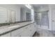 Bathroom featuring double sinks with granite countertops, decorative mirrors, and a tiled walk-in shower at 2309 Redbridge Ln, Apex, NC 27502