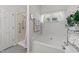 Bright bathroom featuring a large soaking tub with shower head and a curtained window at 2313 Filigree Ct, Raleigh, NC 27614