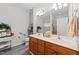 Bright bathroom featuring dual sinks, wood cabinetry, a toilet, shelving with towels, and a large mirror at 2313 Filigree Ct, Raleigh, NC 27614