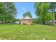 Back view of the house with a large, grassy backyard, trees, and clear blue skies at 310 Wood St, Gibsonville, NC 27249