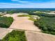 Wide aerial perspective displaying large cultivated land parcel, pond, and dense woodlands at 3187 Wilsons Mills Rd, Smithfield, NC 27577