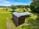 Aerial view of covered outbuildings, pond, and spacious lawn surrounded by trees and fields at 3187 Wilsons Mills Rd, Smithfield, NC 27577