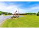 A long, ranch-style brick home on a large lot with driveway, and a sign with an American flag at 3187 Wilsons Mills Rd, Smithfield, NC 27577