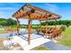 Covered wooden picnic pavilion with bench seating for outdoor dining by a pond on a sunny day at 3187 Wilsons Mills Rd, Smithfield, NC 27577