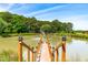 Scenic pond with a wooden dock leading to a fountain, set against a backdrop of lush trees at 3187 Wilsons Mills Rd, Smithfield, NC 27577