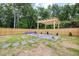 Landscaped backyard with a wooden pergola, stone fire pit, and privacy fence at 389 Whetstone Dr, Angier, NC 27501