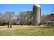 Picturesque view of a grazing cow in a field with a silo and farm buildings at 411 Brampton Close, Pittsboro, NC 27312