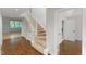 Carpeted staircase with white banister in a room with hardwood floors and a view to a bright, windowed room at 411 Brampton Close, Pittsboro, NC 27312