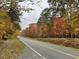 Scenic view of a paved road lined with colorful fall trees along the property at 4451 Poppy Mallow Ln, Oxford, NC 27565