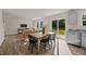 Open-concept dining area adjacent to the living room and kitchen, featuring a wood table, black chairs, and natural light at 552 Stream Walk Xing, Wendell, NC 27591