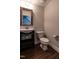 Stylish half bathroom with a vessel sink, dark vanity, toilet, and access to the staircase at 5638 Wade Park Blvd, Raleigh, NC 27607