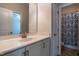 Well-lit bathroom features a large mirror, vanity with sink, and a shower with patterned curtain at 5638 Wade Park Blvd, Raleigh, NC 27607