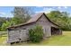 Weathered barn with a metal roof, and wood construction surrounded by greenery on a sunny day at 7404 Halifax Rd, Youngsville, NC 27596