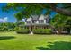 Inviting two-story home features a spacious wraparound porch, lush landscaping, and verdant lawn at 80 Shambley Meadows Dr, Pittsboro, NC 27312