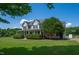 Stunning two-story home with a wraparound porch, green lawn, and mature trees creating a picturesque setting at 80 Shambley Meadows Dr, Pittsboro, NC 27312