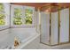 Bright bathroom features a luxurious tub, a glass-enclosed shower, and large windows providing plenty of natural light at 100 Silver Lining Ln, Cary, NC 27513