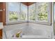 Large, white soaking tub is surrounded by natural light, and complemented by gold fixtures, and tile flooring at 100 Silver Lining Ln, Cary, NC 27513