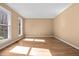 Empty bedroom with hardwood floors and windows overlooking a tree-lined street at 100 Silver Lining Ln, Cary, NC 27513