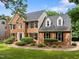 A two story home with brick facade, dormer windows, and manicured landscaping on a sunny day at 100 Silver Lining Ln, Cary, NC 27513