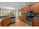 Well-lit kitchen featuring wood cabinets, granite counters, stainless steel appliances, and hardwood floors at 100 Silver Lining Ln, Cary, NC 27513