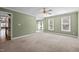 Spacious living room with neutral carpet, soft green walls, large windows, and decorative ceiling fan at 100 Silver Lining Ln, Cary, NC 27513