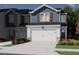 New two-story townhome exterior, featuring an attached garage, concrete driveway, manicured lawn, and colorful flowerbeds at 1027 Winding Spring Dr, Mebane, NC 27302