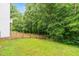 A tranquil, fenced backyard featuring a lush lawn, mature trees, and natural border for privacy at 104 Edgewater Cir, Chapel Hill, NC 27516