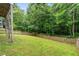 A tranquil, fenced backyard featuring a lush lawn, mature trees, and natural border for privacy at 104 Edgewater Cir, Chapel Hill, NC 27516