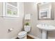 Cozy powder room with pedestal sink and modern fixtures under a window at 104 Edgewater Cir, Chapel Hill, NC 27516