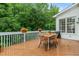 Outdoor deck with a table, four chairs, grill, and lush greenery at 104 Edgewater Cir, Chapel Hill, NC 27516