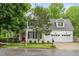 Inviting two-story home with a manicured lawn, a three-car garage, and classic white siding at 104 Edgewater Cir, Chapel Hill, NC 27516