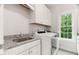 Bright laundry room features white cabinets, granite countertops and stainless sink at 119 Eagles Watch Ln, Chapel Hill, NC 27517