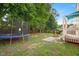 Well-maintained backyard featuring a trampoline, stone patio, and wood deck at 121 River Hills Dr, Clayton, NC 27527
