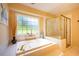Bright bathroom features a luxurious tub next to a large window and a glass-enclosed shower at 121 Walter Hagen Dr, Mebane, NC 27302
