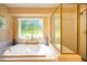 Bright bathroom features a luxurious tub next to a large window and a glass-enclosed shower at 121 Walter Hagen Dr, Mebane, NC 27302