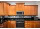 Kitchen featuring wooden cabinets, black countertops, stainless steel appliances, and tile backsplash at 1218 Crystalwater Dr, Fuquay Varina, NC 27526