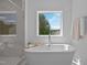 Bright bathroom with a marble walk-in shower and soaking tub beneath a window with wooded views at 1338 The Parks Dr, Pittsboro, NC 27312