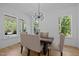 Bright dining room with modern chandelier, wood floors, and views of the wooded yard at 1338 The Parks Dr, Pittsboro, NC 27312