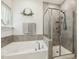 Bright bathroom featuring a soaking tub and glass enclosed shower with gray tile surround at 145 Cassada Ct, Holly Springs, NC 27540