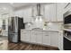 Close-up of a stove top, stainless steel vent hood, and white cabinets at 145 Cassada Ct, Holly Springs, NC 27540