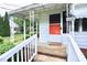 Close-up of the welcoming front porch with a white railing and bright orange door with house number at 2006 N Ashland Dr, Burlington, NC 27217