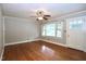 An empty living room shows a ceiling fan and original hardwood floors with large windows at 2006 N Ashland Dr, Burlington, NC 27217