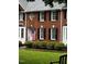 Charming brick townhouse featuring an arched entrance, black shutters, and a well-manicured lawn at 227 Kenmont Dr, Holly Springs, NC 27540