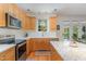Well-lit kitchen with natural wood cabinets, stainless steel appliances, granite counters, and access to the patio at 227 Kenmont Dr, Holly Springs, NC 27540