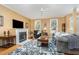 Cozy living room featuring a fireplace, hardwood floors, ceiling fan, and natural light from large windows at 227 Kenmont Dr, Holly Springs, NC 27540