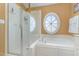 Bright bathroom features a glass shower, soaking tub with jets, and a porthole window at 227 Kenmont Dr, Holly Springs, NC 27540