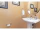 Cozy powder room features pedestal sink, round mirror, and attractive wall decor at 227 Kenmont Dr, Holly Springs, NC 27540
