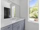 Stylish bathroom featuring gray vanity, large mirror, and natural light from window at 2805 Van Dyke Ave, Raleigh, NC 27607