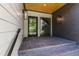 Inviting covered front porch with brick flooring, black framed glass door, and stylish exterior lighting at 2805 Van Dyke Ave, Raleigh, NC 27607